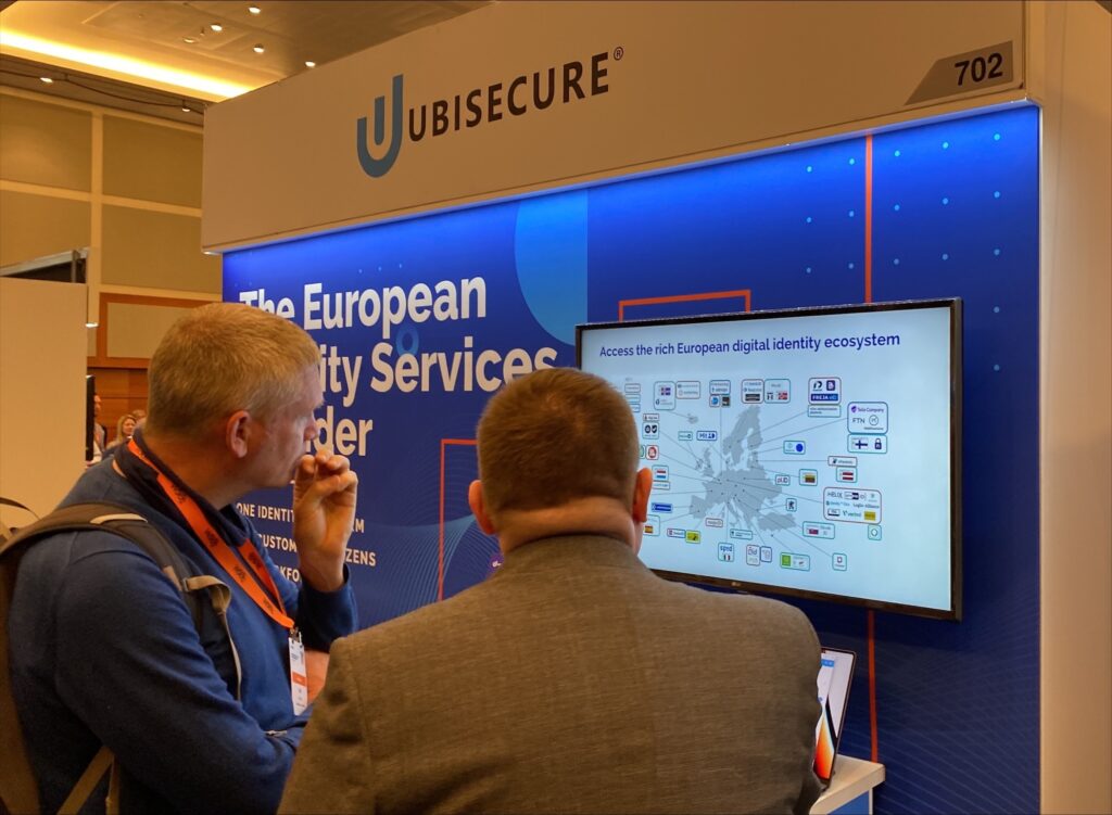 Ubisecure team member and event attendee looking at information on presentation slide, on the Ubisecure booth at Gartner IAM 2022.